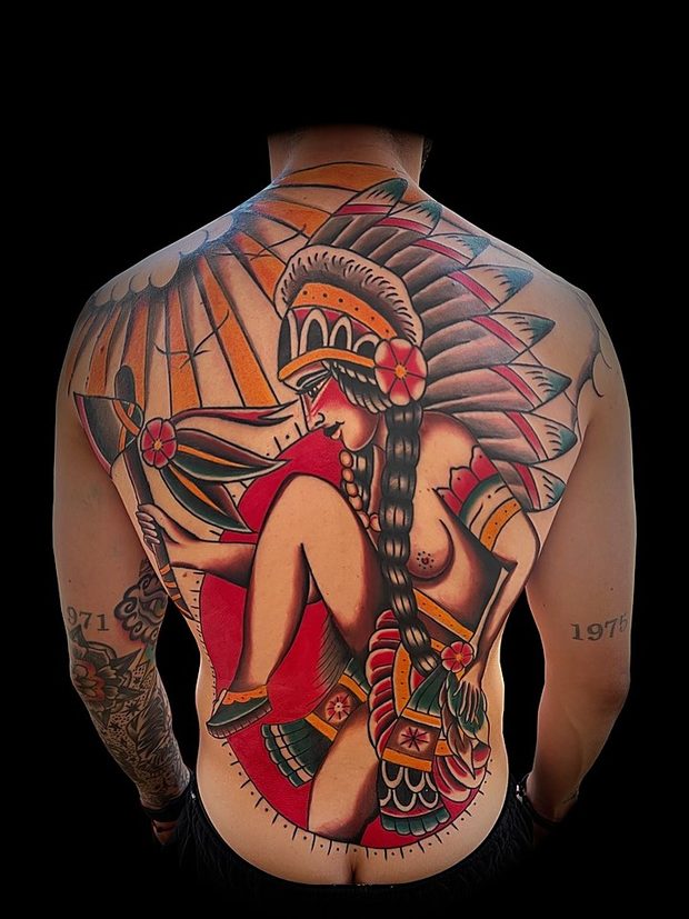 Full back tattoo of a figure in a feathered headdress by Penny Boy — neo-traditional colour back piece