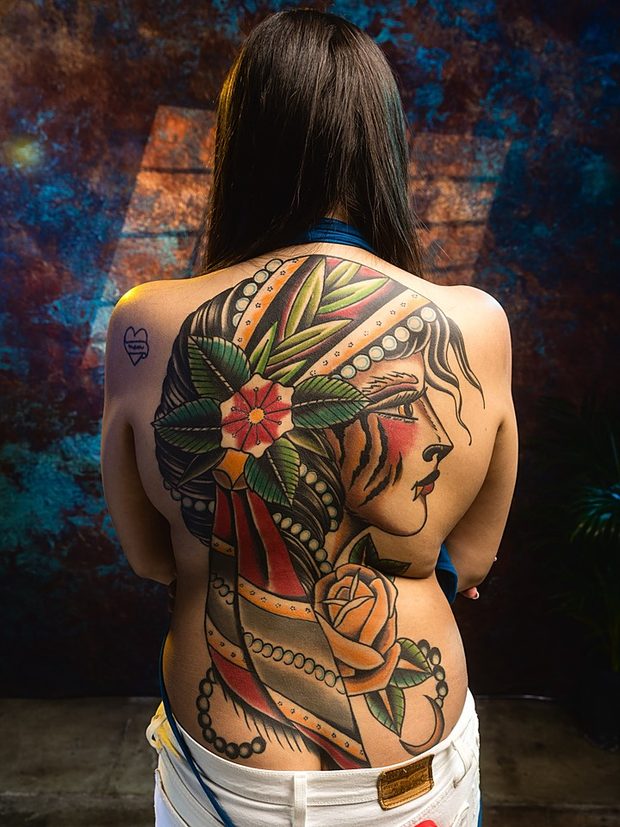 Neo-traditional full back tattoo of a ladyhead in an emerald headdress by Penny Boy — large-scale colour back piece